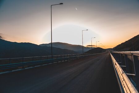 Beautiful asphalt road. Colorful landscape with high rocks, mountain road with a perfect asphalt, trees and amazing sunny cloudy sky at sunset in summer. Travel background. Highway at mountains. Roadの写真素材