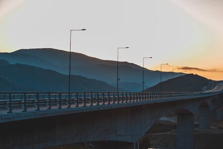 Beautiful asphalt road. Colorful landscape with high rocks, mountain road with a perfect asphalt, trees and amazing sunny cloudy sky at sunset in summer. Travel background. Highway at mountains. Roadの写真素材