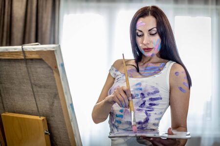 Young woman artist painting at home creative tools close-upの写真素材