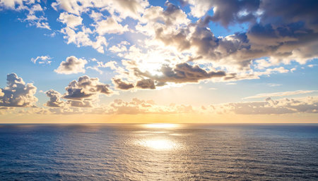 Sunset over the ocean with clouds on blue sky and sun raysの素材