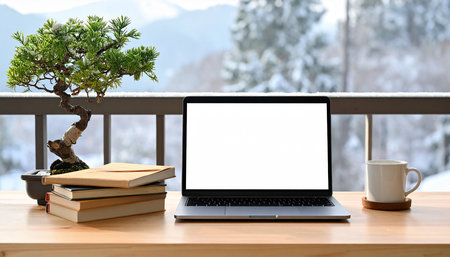 Laptop with blank screen on wooden table with books and bonsai tree.の素材