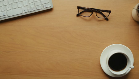 Coffee cup with eyeglasses and keyboard on wooden tableの素材