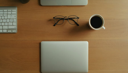 Top view of laptop, coffee cup and eyeglasses on wooden tableの素材