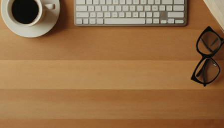 Office desk table with keyboard, coffee cup and eyeglasses. Top view with copy spaceの素材