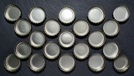 close up of beer bottle caps on a black background, top viewの素材