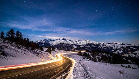 Night view of the snowy mountains and a long exposure car light trailsの素材
