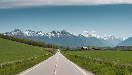 country road in springtime with snow capped alps in the backgroundの素材
