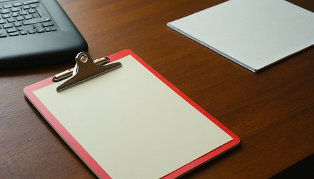 Blank white paper on clipboard with laptop on the wooden table.の素材