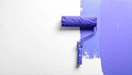 Roller with blue paint on a white background, close-upの素材