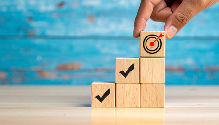 Business target and goal achievement concept. Businessman hand put wooden cube with dartboard on top.の素材