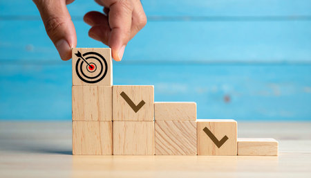 Businessman hand placing wooden block with check mark on top of target for success concept.の素材