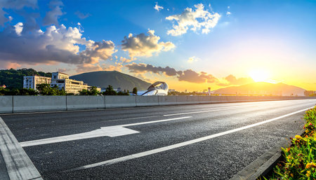 Asphalt road and city skyline with buildings and blue sky at sunsetの素材