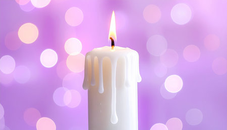 Burning candle on purple bokeh background, close-upの素材