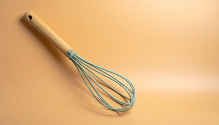 Kitchen utensils. A whisk on a beige background.の素材