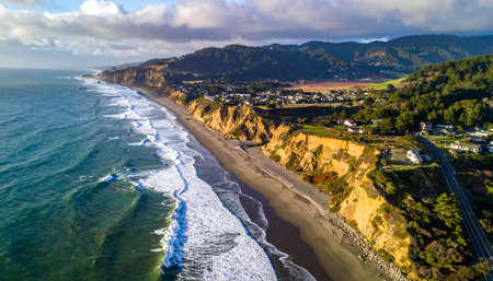 Aerial view of a coastal town with houses on cliffs overlooking the Pacific Ocean and a long sandy beach.の素材