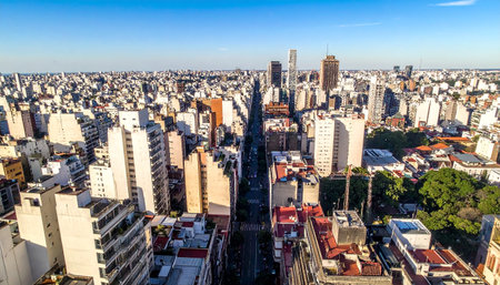 Aerial perspective of a sprawling cityscape with numerous buildings of varying heights and a central avenue.の素材