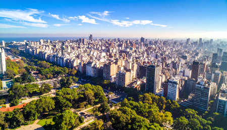 Broad aerial perspective of a vast city featuring extensive green parkland and a distant ocean viewの素材