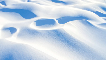 Rippling snow surface with contrasting blue shadows and bright sunlight creating abstract shapes.の素材