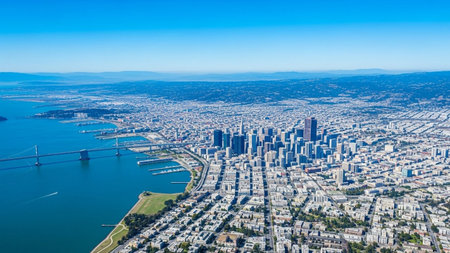 This aerial perspective showcases the vibrant cityscape of San Francisco on a clear, sunny day. The deep blue waters of the bay stretch out to the left, with the iconic Golden Gate Bridge spanning across it. The dense urban area is filled with a multitude of buildings and skyscrapers, forming a dynamic skyline. The captures the city's extensive coastline, harbors, and the surrounding landscape, highlighting its unique geographical setting and urban development.の素材