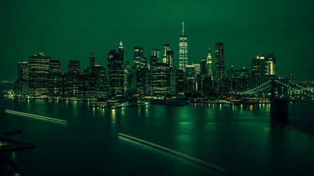 A dramatic panoramic night view of a modern city skyline, predominantly New York City, bathed in an eerie green light. Towering skyscrapers with illuminated windows pierce the dark sky. The city's lights reflect on the dark water in the foreground, where streaks of light indicate moving boats or ferries. A prominent bridge, likely the Brooklyn Bridge, is visible on the right. The overall mood is futuristic, moody, andの素材