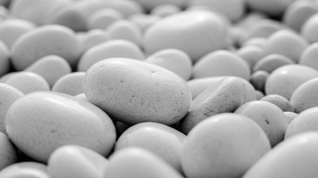 Detailed black and white macro view of smooth, rounded pebbles and stones creating a textured natural pattern and...の素材