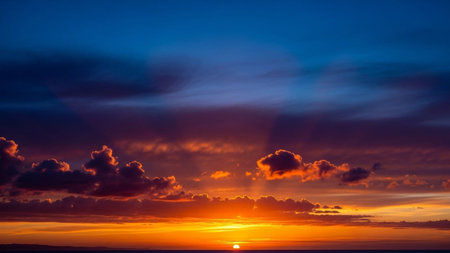 Wispy showing dramatic sunset over the ocean with vibrant orange and blue sky and wispy clouds. resolution...の素材