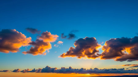 A vibrant sunset paints the sky with fiery orange and pink clouds, casting a warm glow over the darkening horizon.の素材