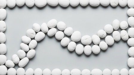 20251228 showing arrangement of smooth white pebbles forming a wavy line within a rectangular border on a light gray...の素材