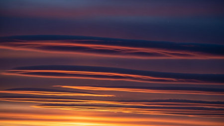20251228 showing dramatic sunset sky with horizontal lenticular clouds in fiery orange and deep purple hues.の素材