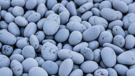 A dense pile of smooth, rounded white and gray river stones creating a textured natural background.の素材