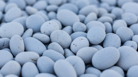 A dense collection of smooth, rounded white and light gray pebbles and stones forming a textured natural background...の素材