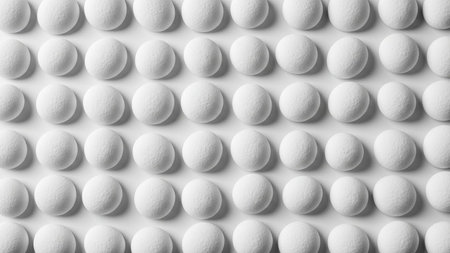 A grid of numerous white round pills or tablets arranged in neat rows and columns on a bright white surface.の素材