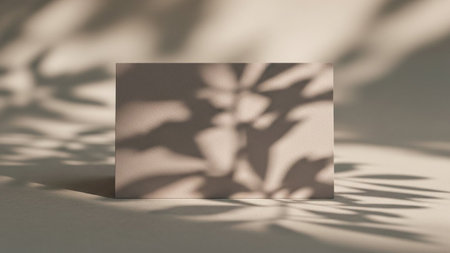 A close-up view of a neutral, textured surface, possibly paper or fabric, bathed in soft, diffused light. Intricate shadow patterns of leaves are cast across the surface, creating an organic and abstract The shadows are soft-edged and layered, suggesting dappled sunlight filtering through foliage. The color palette is muted and calming, with shades of beige and cream. is use as a subtle background or overlay, adding a touch of natural elegance and tranquility toの素材