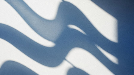 Soft blue wave shadows are cast across a textured white wall, creating a gentle, flowing abstract pattern with...の素材