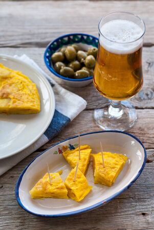 Spanish tortilla de patatas, olives and beer on antique woodの写真素材