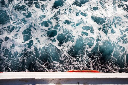 Top view of sea foam and waves next to a boatの写真素材