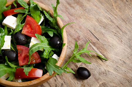 Greek salad in a wooden salad bowl on the table の写真素材