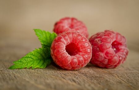 Three sweet ripe raspberries on a wooden table