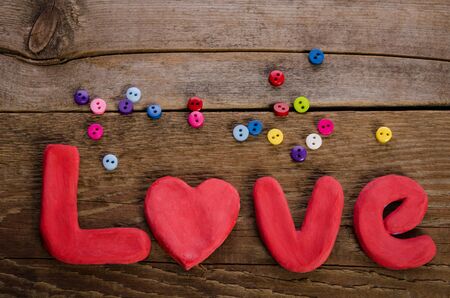 The word LOVE and colorfull buttons on wooden backgroundの写真素材