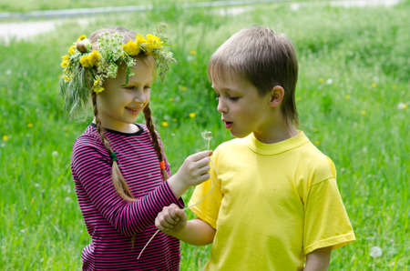 Boy and girl are Standing Blowing Dandelions In Fieldの写真素材