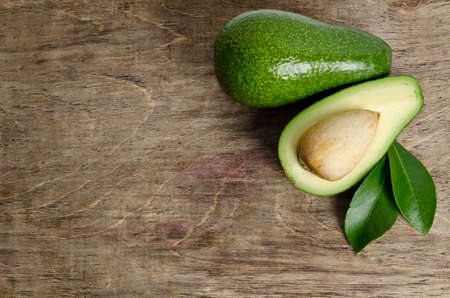 fresh avocado with leaves on wooden backgroundの写真素材