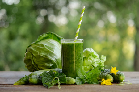 glass with green smoothie on a wooden table and  vegetables with mint leavesの写真素材