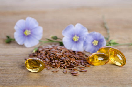 Flax seeds , beauty flowers and oil in caps on wooden background. Phytotherapy. 