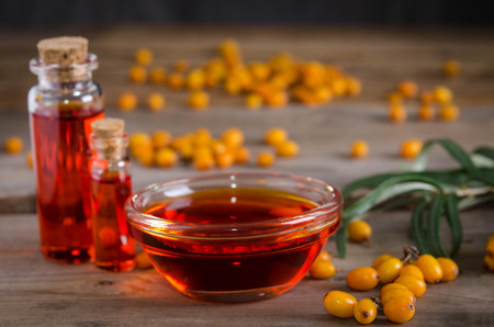 Sea buckthorn with bottle with sea buckthorn oil  on wooden table 