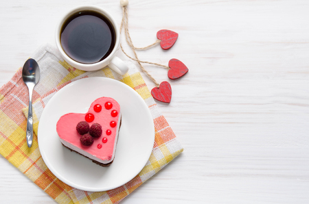 souffle cake in the form of heart  with cup of coffee on a wooden tableの写真素材