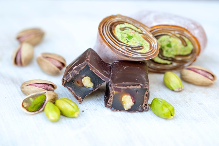 Eastern Turkish sweets with pistachios on a white wooden background. Chocolate candy with pistachios, baklava and pistachio nuts around.の写真素材