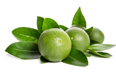 green limes with leaves isolated on white backgroundの写真素材