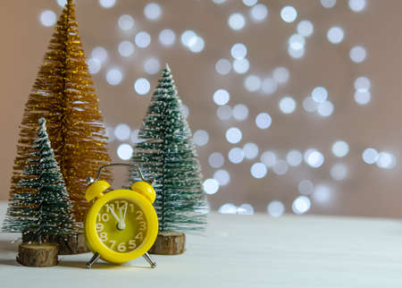 Yellow alarm clock and a Christmas tree on the table. Christmas decorations