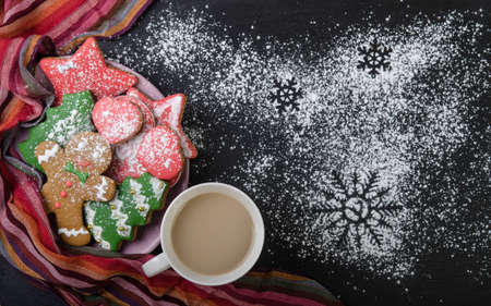 Multi-colored gingerbread cookies in a bowl and cocoa in a cup on a black top. Christmas decoration.の写真素材