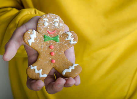 Close-up shot of a gingerbread man in right hand. Christmas decoratiion.
